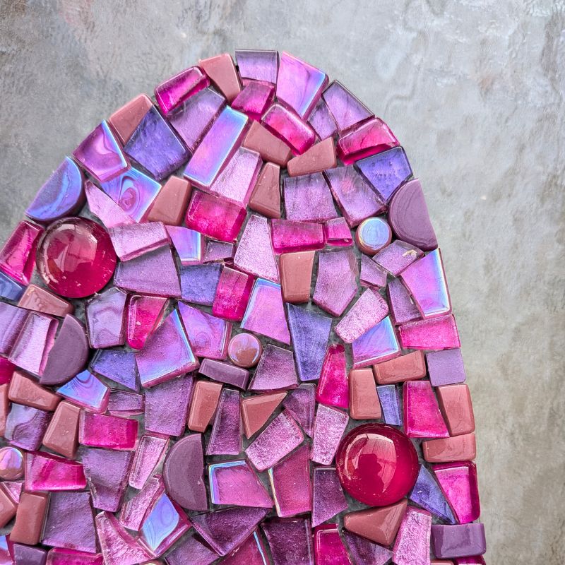 a range of pink coloured glass mosaic tiles glued into place showing how the fabricated edge creates a clean, neat outside edge of the artwork